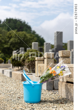 お墓詣りの時に仏花をお墓にお供えしようとしているところ お墓詣りの時に仏花をお墓にお供えしようとしているところ 92874903