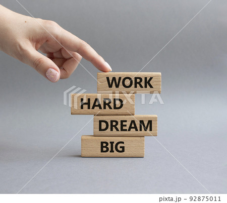 Work and dream symbol. Wooden blocks with words 'Work Hard Dream Big'. Beautiful grey background. Businessman hand. Business and Work Hard Dream Big concept. Copy space. Work and dream symbol. Wooden blocks with words 'Work Hard Dream Big'. Beautiful grey background. Businessman hand. Business and Work Hard Dream Big concept. Copy space. 92875011