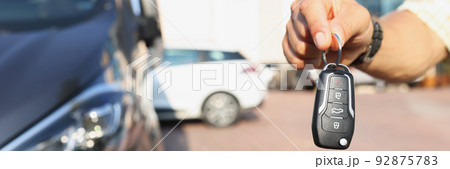 A hand near the car holds an electronic key, close-up A hand near the car holds an electronic key, close-up 92875783
