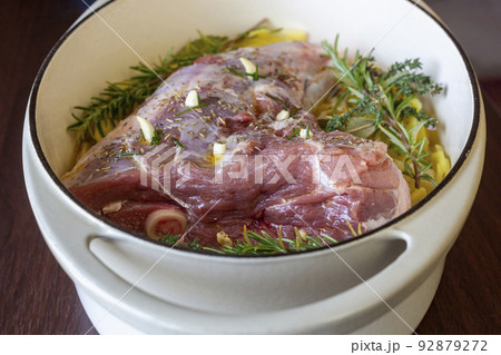 Raw leg of lamb prepared to cook with sliced potatoes and provencal herbs 92879272