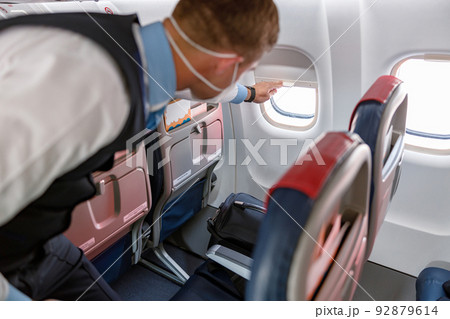 Male flight attendant closing window in aircraft Male flight attendant closing window in aircraft 92879614