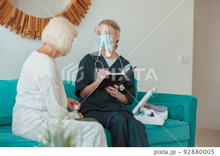 Nurse checking health of senior woman in living room Nurse checking health of senior woman in living room 92880005
