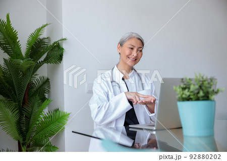 Asian female physician communicating in sign language with patient by video 92880202