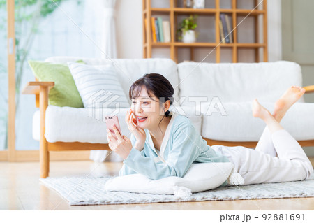 リビングでスマホを見る若い女性 リビングでスマホを見る若い女性 92881691