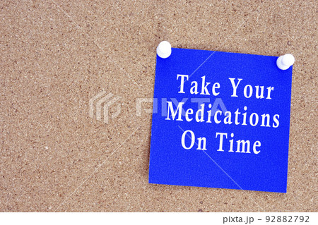 Take your medications on time text on stick note on a cork notice board. Take your medications on time text on stick note on a cork notice board. 92882792