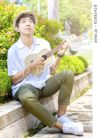 Asian man with hat playing guitar ukulele 92883429