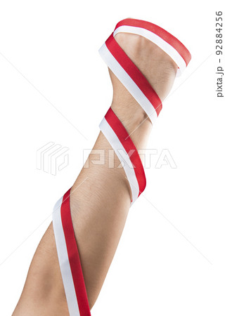 Human hand holding a ribbon with the red and white color of the Indonesian flag Human hand holding a ribbon with the red and white color of the Indonesian flag 92884256