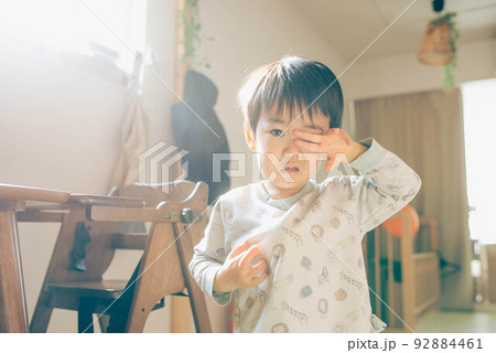 眠そうに目をこすりながらカメラを見つめる子ども 92884461