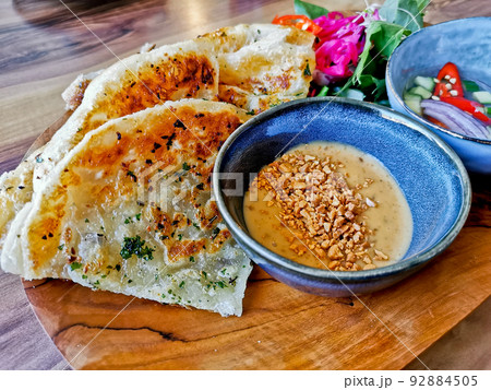 Garlic naan roti lightly grilled flat bread with peanut satay sauce and garden salad and cucumber vinegar relish 92884505