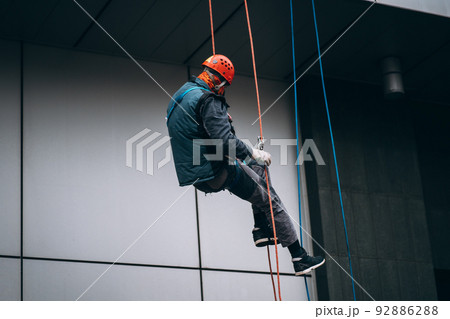 Industrial climber in uniform and helmet rises 92886288