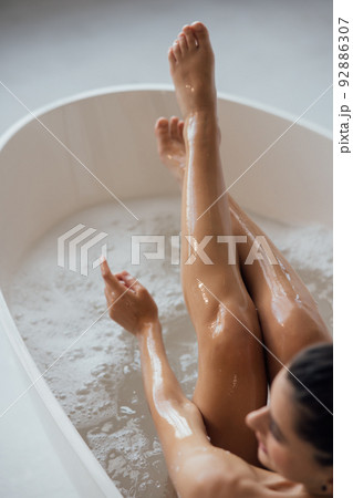 Pretty young woman taking bath at home back view 92886307