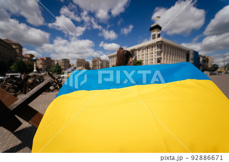 Young woman carries the flag of Ukraine fluttering behind her Young woman carries the flag of Ukraine fluttering behind her 92886671