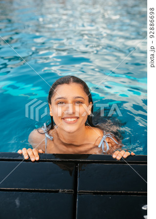 Young woman resting on the edge of swimming poolの写真素材