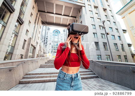 Woman in a virtual reality helmet walks down the street 92886799