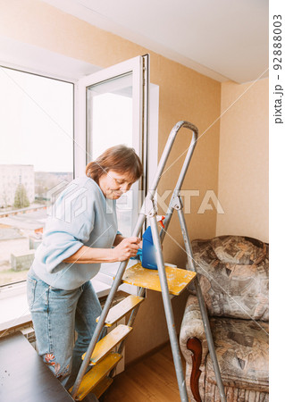 Happy Shy Mature Woman Cleaning House. Concept Of Household And People In Retirement. Elderly Woman Cleaning Apartment. Independent Senior Woman On Stepladder. Housewife. Caucasian Woman Middle Age 92888003