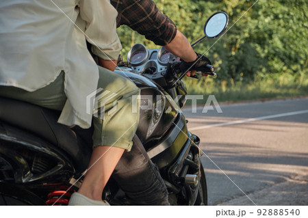 Legs close up Middle age couple riding a motorcycle, traveling together on a forest road Legs close up Middle age couple riding a motorcycle, traveling together on a forest road 92888540