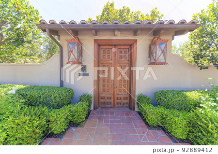 Wooden door gate entrance with orange wall lamps and doorbell on the post at La Jolla, California Wooden door gate entrance with orange wall lamps and doorbell on the post at La Jolla, California 92889412