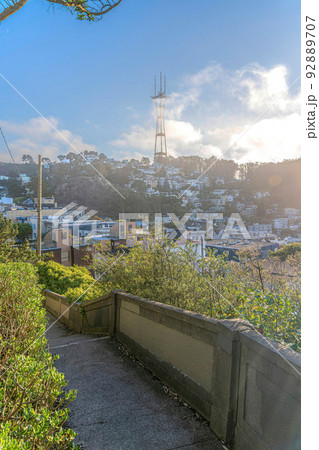 View of Sutro Tower against the clouds from a concrete pathway with barriers in San Francisco, CA 92889707