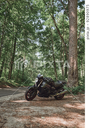 Black road bike on the roadside of a forest road, no people 92890975