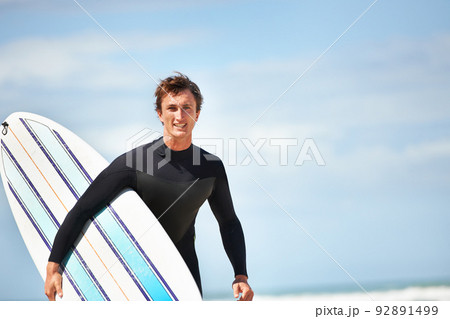 Its just me and my surfboard. Portrait of a young surfer at the beach on a sunny day. 92891499