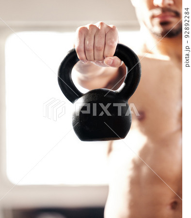 Hold this will you. Cropped shot of a young man working out with a kettle bell in a gym. 92892284