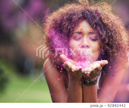 Painting the world pink. Shot of an attractive young woman blowing purple paint powder at the camera. 92892442
