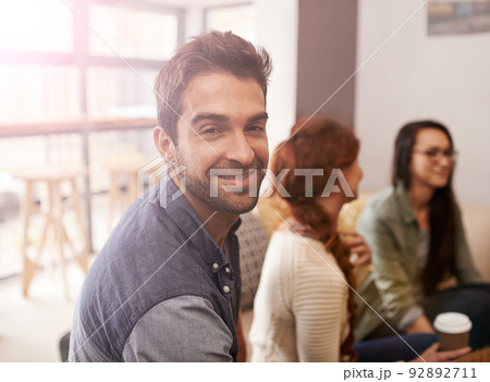 We all have something in common, coffee. Portrait of a young sitting in a coffee shop with his friends blurred in the background. 92892711