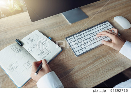 Close up of business woman hands working using keyboard of computer and making notes in office 92892716