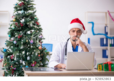 Young male doctor celebrating Christmas at the hospital Young male doctor celebrating Christmas at the hospital 92892863