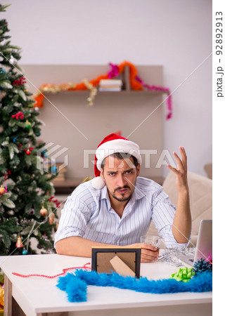 Young man celebrating Christmas at home alone Young man celebrating Christmas at home alone 92892913