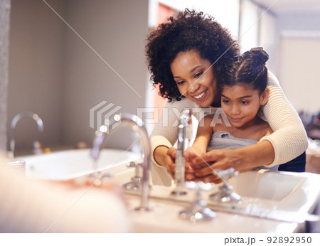Lets get them good and clean. Cropped shot of a mother and daughter washing their hands at the bathroom sink. 92892950