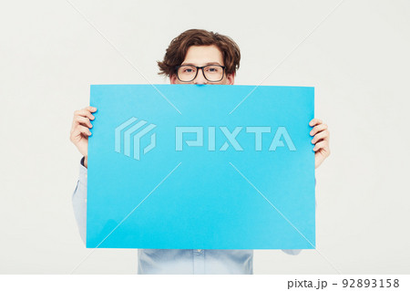 Come on over and put your copy here. A young man holding a blue placard up for your copyspace. Come on over and put your copy here. A young man holding a blue placard up for your copyspace. 92893158