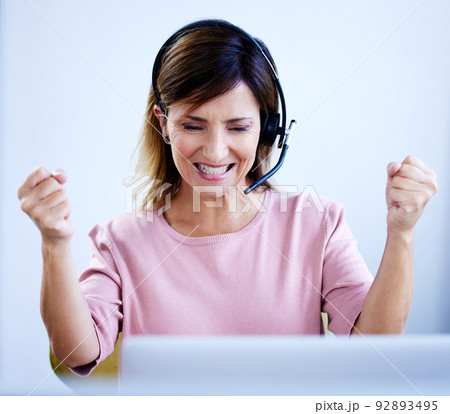 Winning in the sales game. Shot of a mature call centre agent cheering while working on a laptop in an office. Winning in the sales game. Shot of a mature call centre agent cheering while working on a laptop in an office. 92893495