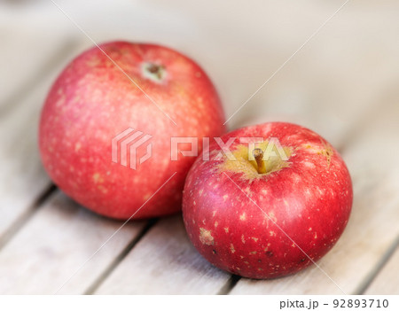 Two red apples on a wooden table indoors. Eat healthy and watch your diet. Fruit contains essential vitamins to boost your immunity. Closeup of a delicious snack vegans and vegetarians can enjoy Two red apples on a wooden table indoors. Eat healthy and watch your diet. Fruit contains essential vitamins to boost your immunity. Closeup of a delicious snack vegans and vegetarians can enjoy 92893710