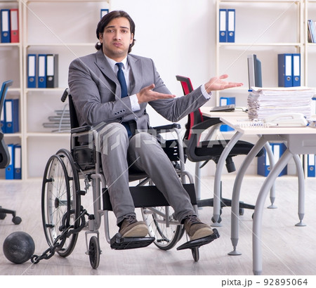 Young handsome employee in wheelchair working in the office 92895064