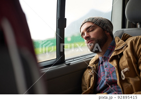 Exhausted after a long days travels. Shot of a handsome asleep in the back seat of a travelling vehicle. Exhausted after a long days travels. Shot of a handsome asleep in the back seat of a travelling vehicle. 92895415