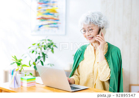 電話をしながら仕事をするシニア女性 92895547