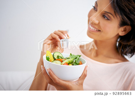 For a taste that inspires. Shot of a young woman enjoying a salad at home. 92895663