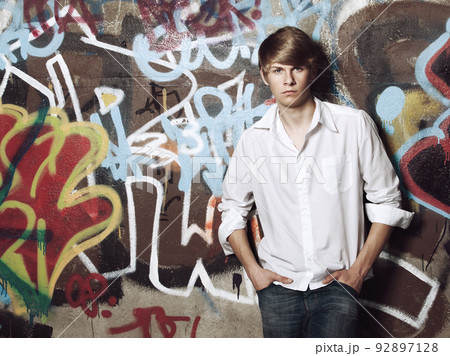 My lifestyle, my choice. Portrait of a trendy teenage boy posing against a spray painted wall. My lifestyle, my choice. Portrait of a trendy teenage boy posing against a spray painted wall. 92897128