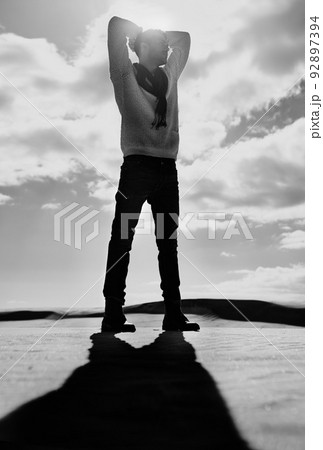 Man versus the elements. Full length monochrome shot of a man standing in a desert landscape. 92897394