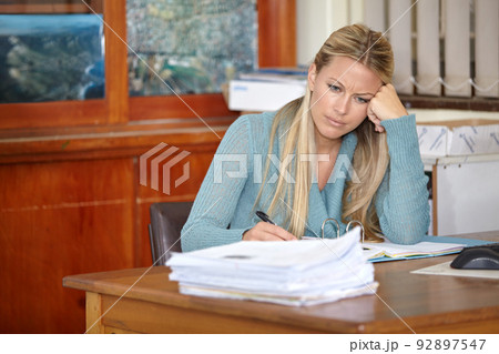 The busy life of a teacher. A tired young teacher sitting at her classroom desk marking classwork and tests. The busy life of a teacher. A tired young teacher sitting at her classroom desk marking classwork and tests. 92897547