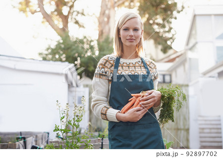 Organic gardening. A young woman holding carrots in her garden. Organic gardening. A young woman holding carrots in her garden. 92897702