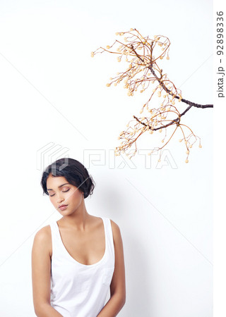 As beautiful as spring itself. Studio shot of an attractive young ethnic woman sitting under a branch. As beautiful as spring itself. Studio shot of an attractive young ethnic woman sitting under a branch. 92898336