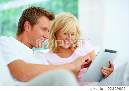 Happy couple using tablet pc. Happy couple sitting on a sofa using tablet pc. 92899005