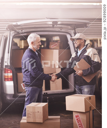 Delivered by the best in the business. Shot of two delivery men shaking hands next to a van filled with boxes. 92899009