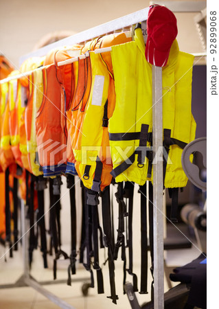 Ready when needed. Cropped shot of life jackets hanging on a rail inside a lifeguard station. 92899068