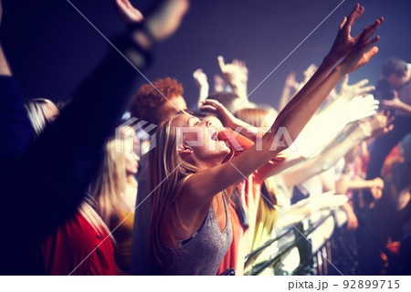 Enjoying the music. A group of people standing with their arms raised at a concert. 92899715