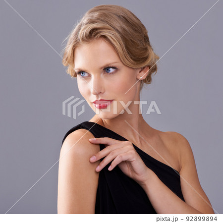 Nothing but elegance. A gorgeous young woman in an evening gown while isolated on a grey background. 92899894