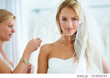 Putting on the final touches. A young woman trying on wedding dresses in a bridal boutique. Putting on the final touches. A young woman trying on wedding dresses in a bridal boutique. 92900284