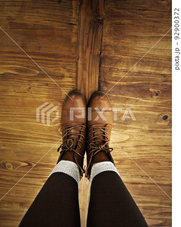 Rustic style. POV shot of a person wearing boots standing on a wooden floor. Rustic style. POV shot of a person wearing boots standing on a wooden floor. 92900372